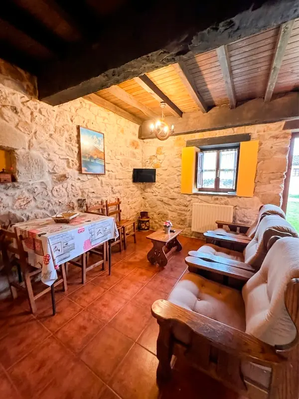 Salón rústico con paredes de piedra y techos de madera en nuestro apartamento rural cerca de Arriondas.